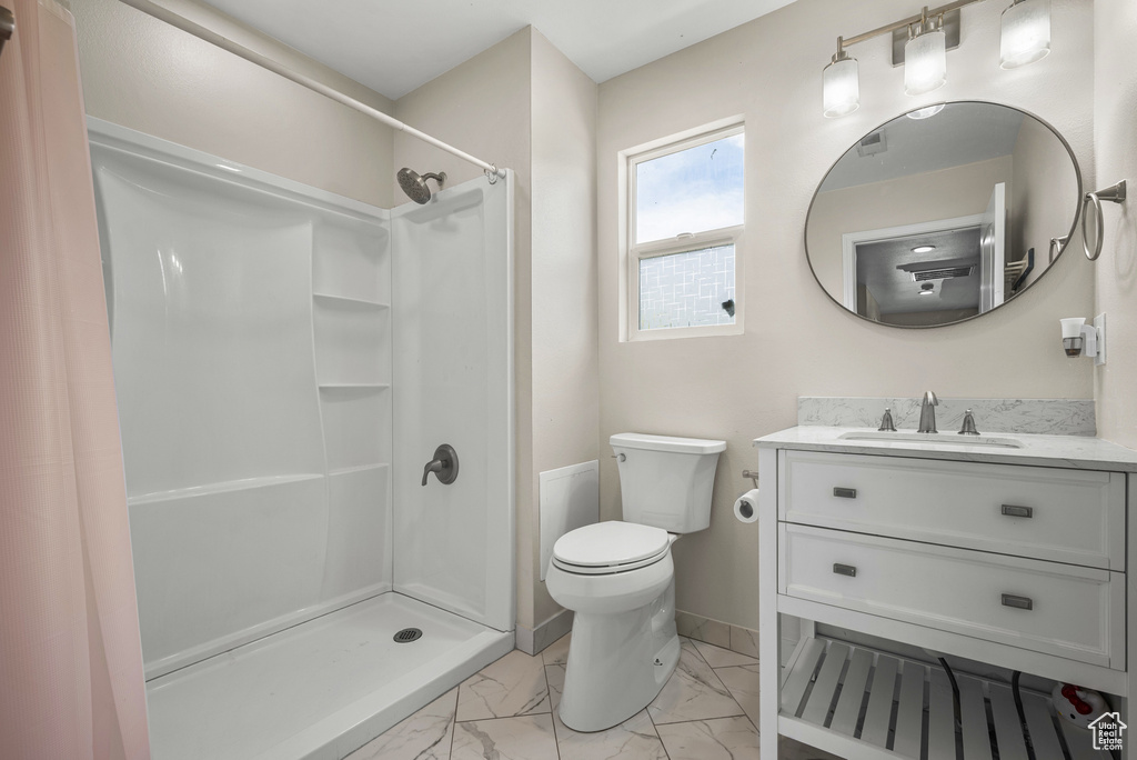Full bathroom featuring marble look tiles, a shower stall, toilet, vanity, and baseboards