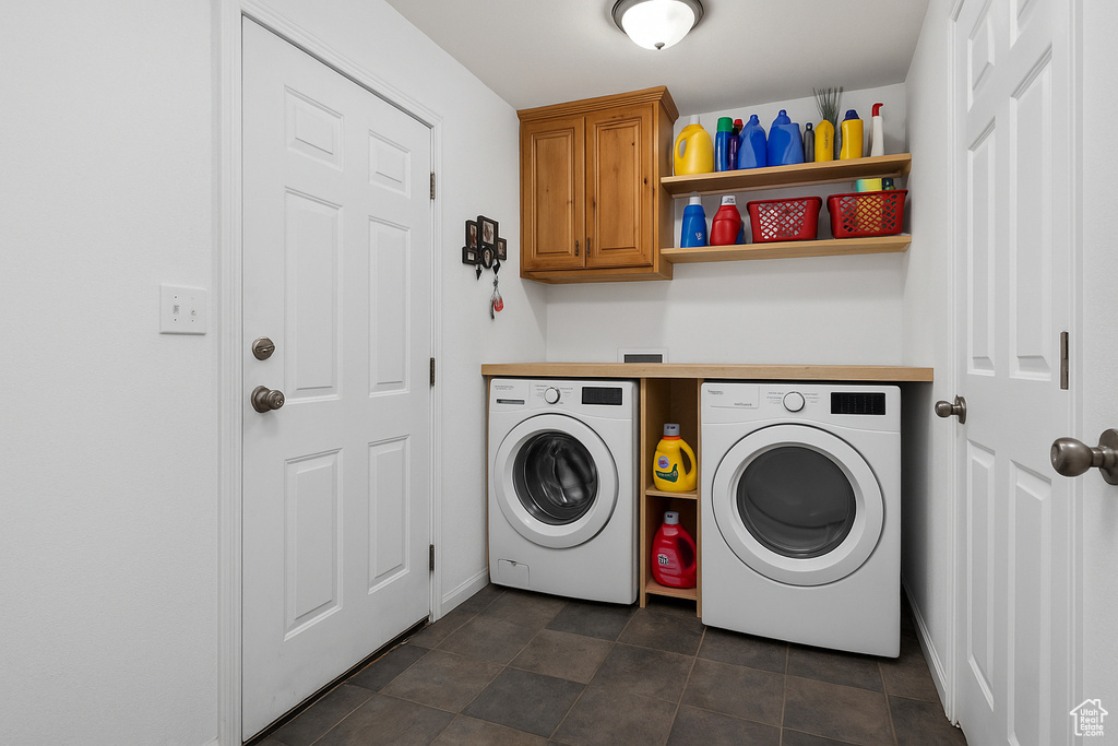 Clothes washing area with separate washer and dryer, cabinet space, and baseboards