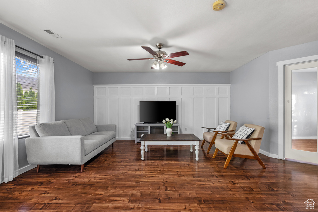 Living room with ceiling fan, dark wood-style flooring, and baseboards