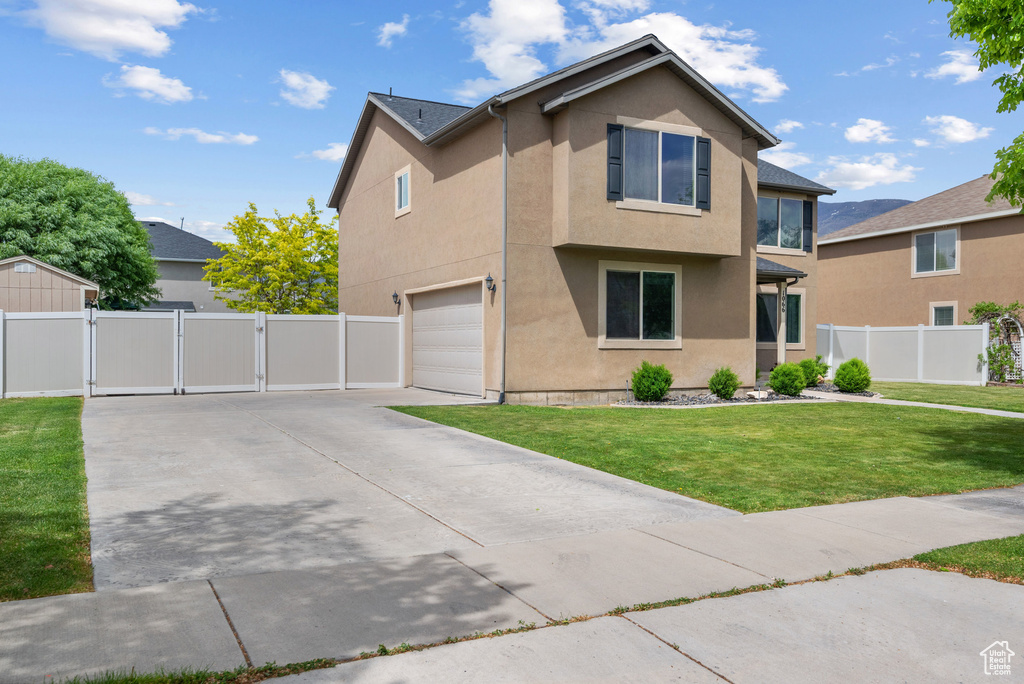 Traditional-style house featuring a gate, stucco siding, an attached garage, and concrete driveway