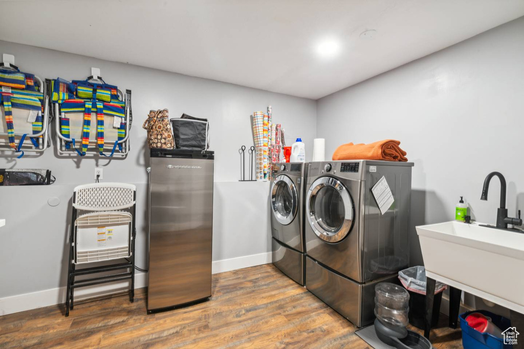 Clothes washing area featuring washing machine and dryer, wood finished floors, and baseboards