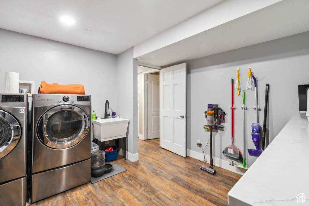 Laundry room with wood finished floors, washer and clothes dryer, and baseboards
