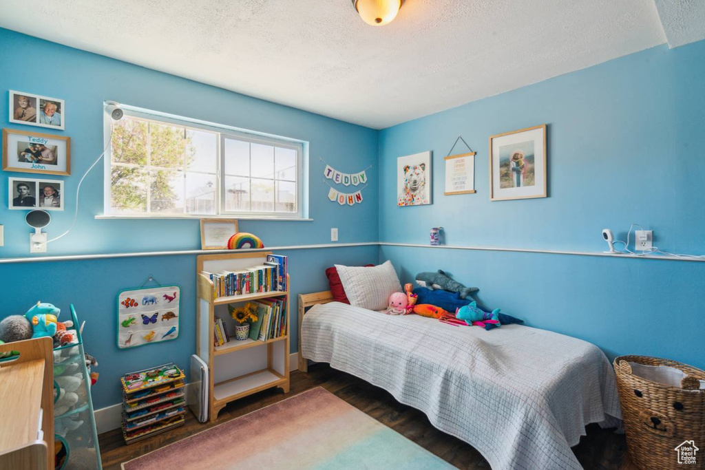 Bedroom with wood finished floors, baseboards, and a textured ceiling