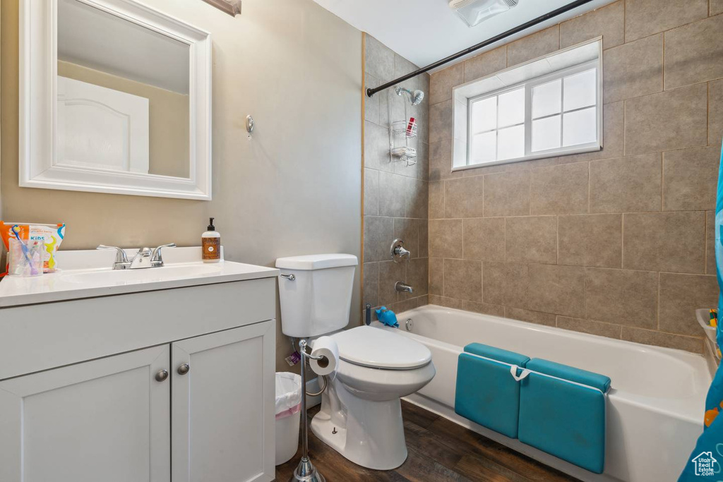 Full bath with wood finished floors, toilet, vanity, and tub / shower combination