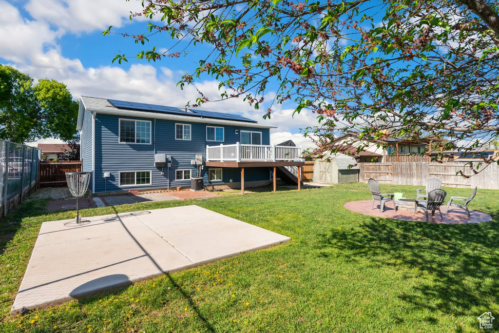 Back of house featuring a fire pit, a patio area, a deck, roof mounted solar panels, and stairs