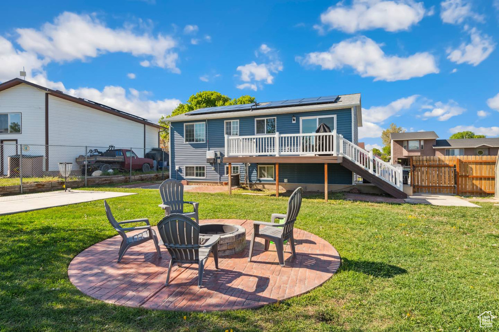 Back of property featuring stairs, a fire pit, solar panels, a deck, and a patio area