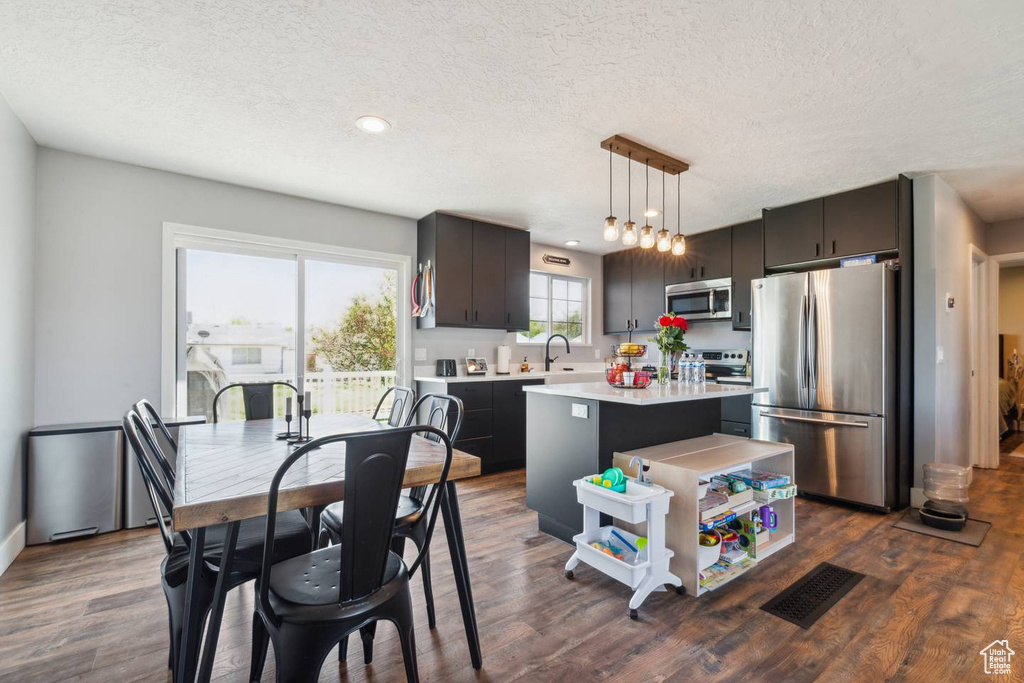 Kitchen with stainless steel appliances, light countertops, a sink, a textured ceiling, and dark wood-type flooring