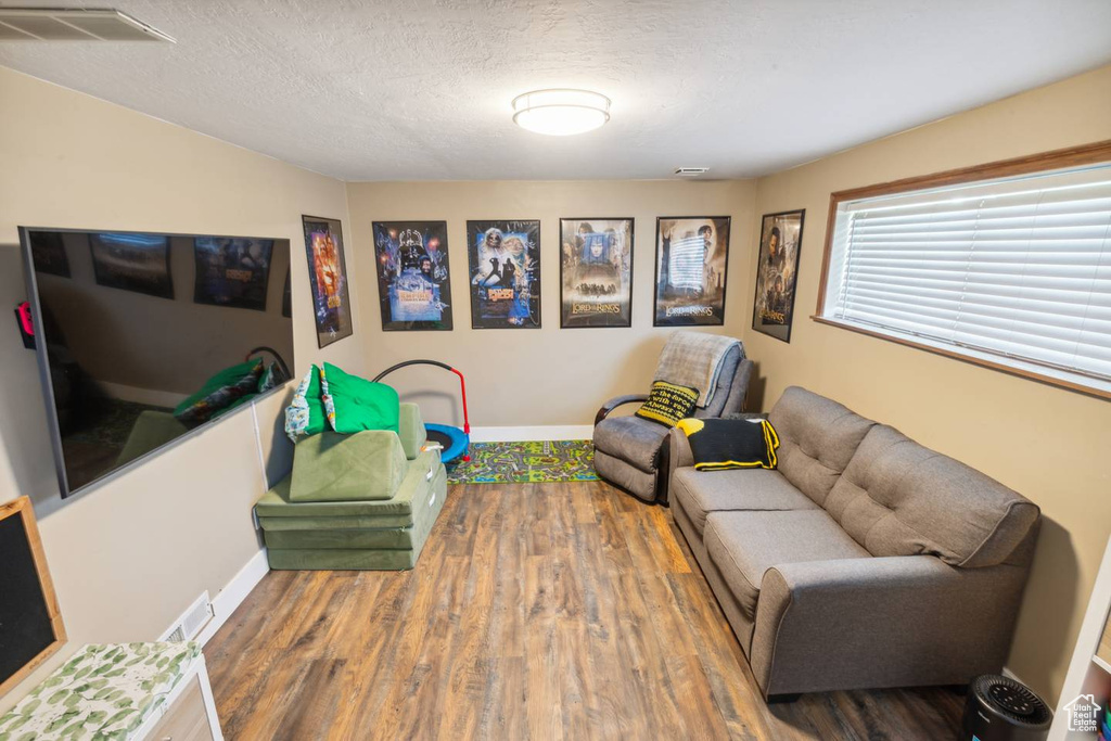 Living room with wood finished floors, baseboards, and a textured ceiling