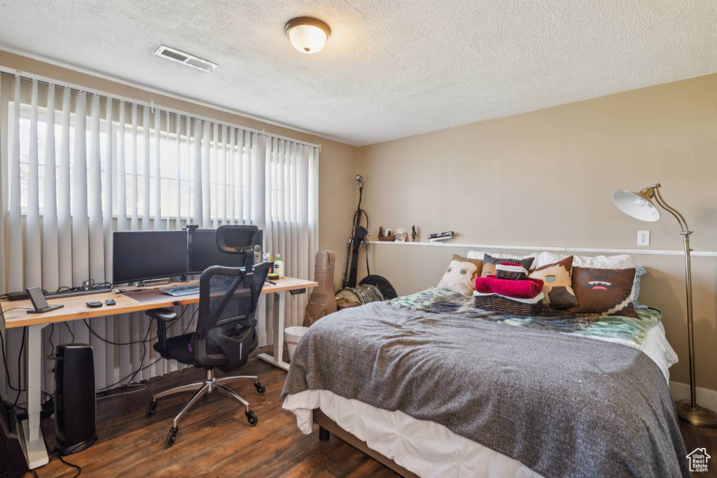 Bedroom featuring wood finished floors, a textured ceiling, and a desk