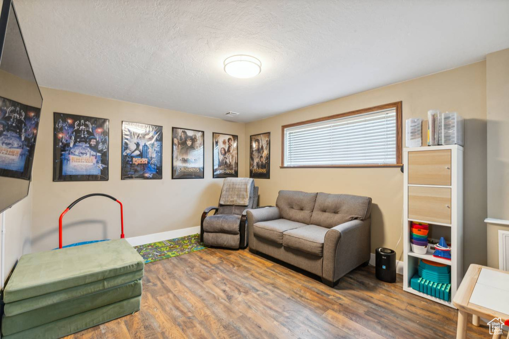 Living room featuring wood finished floors, baseboards, and a textured ceiling
