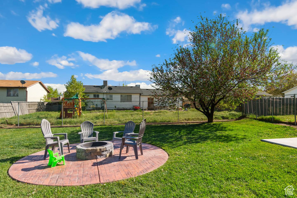 View of yard with an outdoor fire pit, a patio area, and a playground
