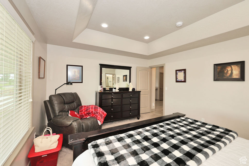 Carpeted bedroom featuring recessed lighting and a tray ceiling