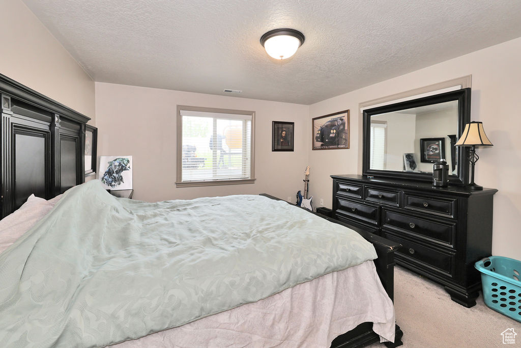 Bedroom with light carpet and a textured ceiling