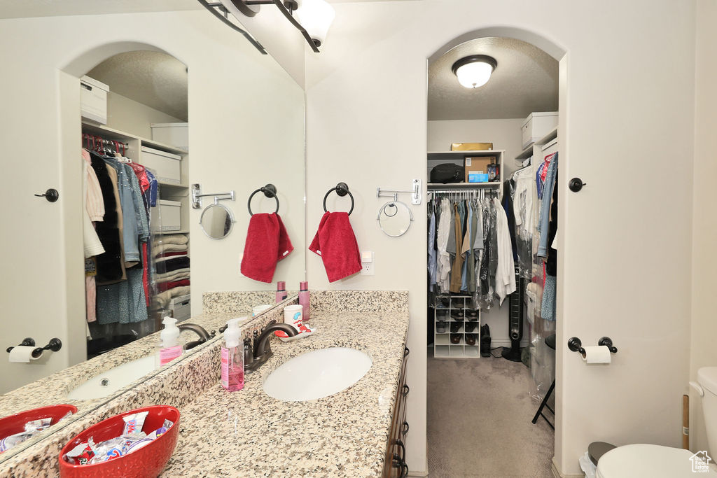 Bathroom with vanity, toilet, and a walk in closet