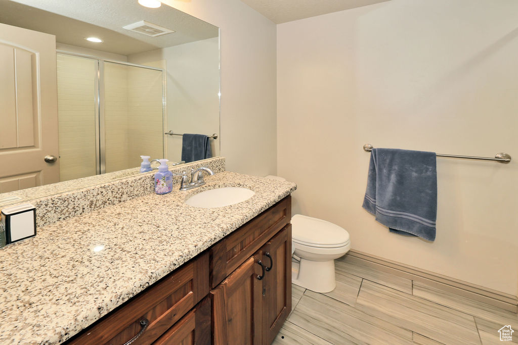 Full bathroom featuring a shower stall, toilet, vanity, wood finish floors, and recessed lighting
