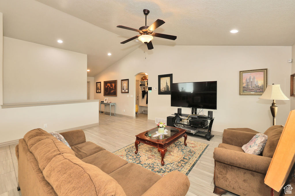 Living room featuring arched walkways, a ceiling fan, vaulted ceiling, baseboards, and recessed lighting