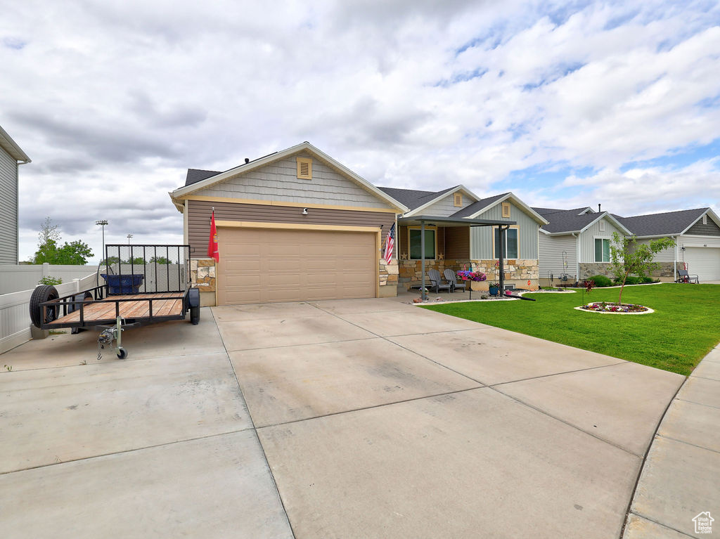 View of front of property featuring a garage, driveway, stone siding, and board and batten siding
