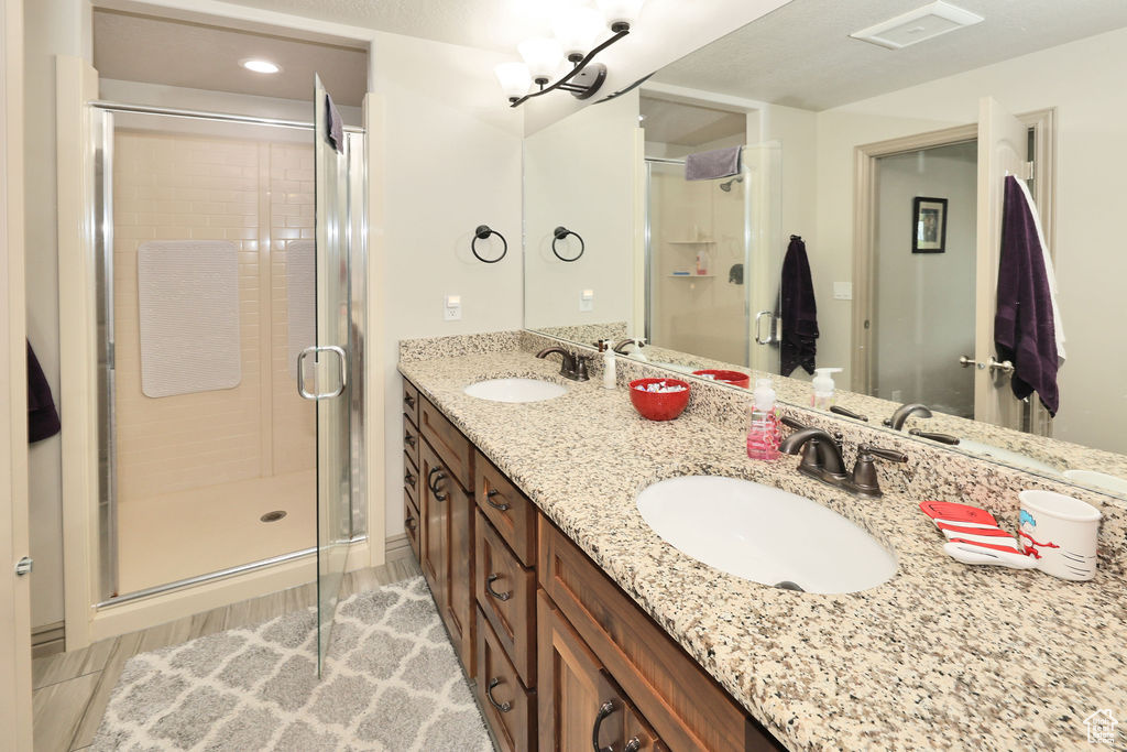 Bathroom with a stall shower, wood finished floors, and double vanity