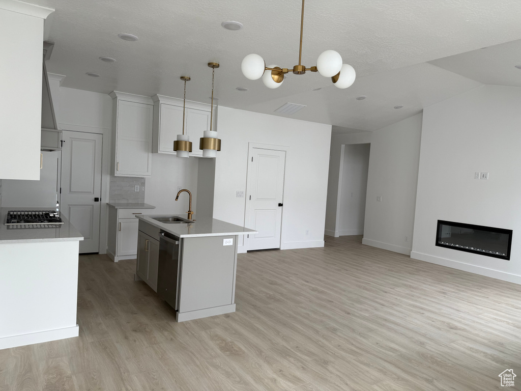 Kitchen featuring stainless steel dishwasher, light wood-style flooring, a sink, an island with sink, and gas stovetop