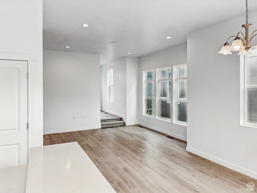 Empty room featuring a chandelier, wood finished floors, baseboards, and recessed lighting