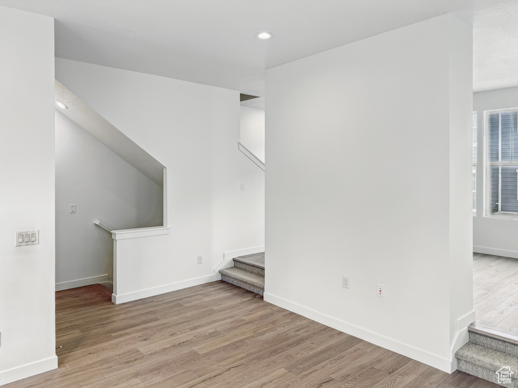 Unfurnished living room featuring stairs, light wood-style flooring, recessed lighting, and baseboards