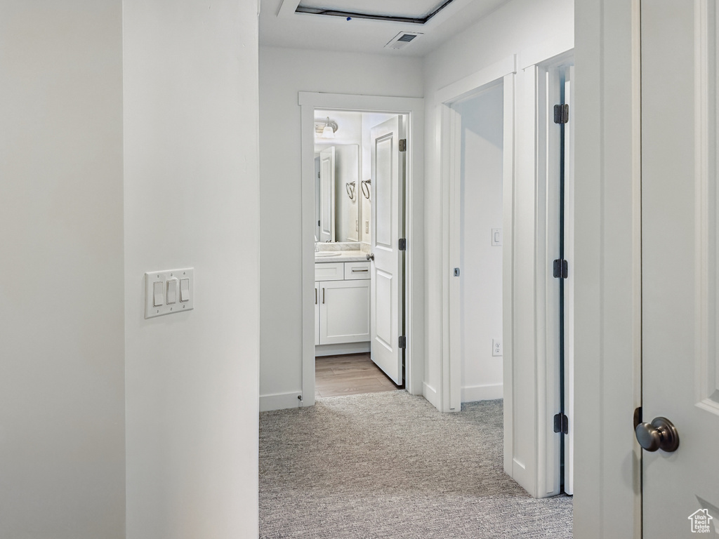Hallway with light colored carpet and baseboards
