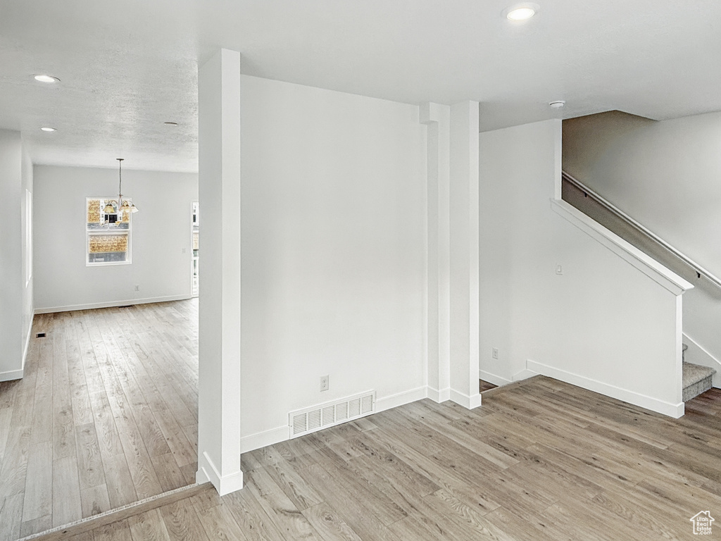 Unfurnished living room with stairs, wood finished floors, recessed lighting, baseboards, and a chandelier