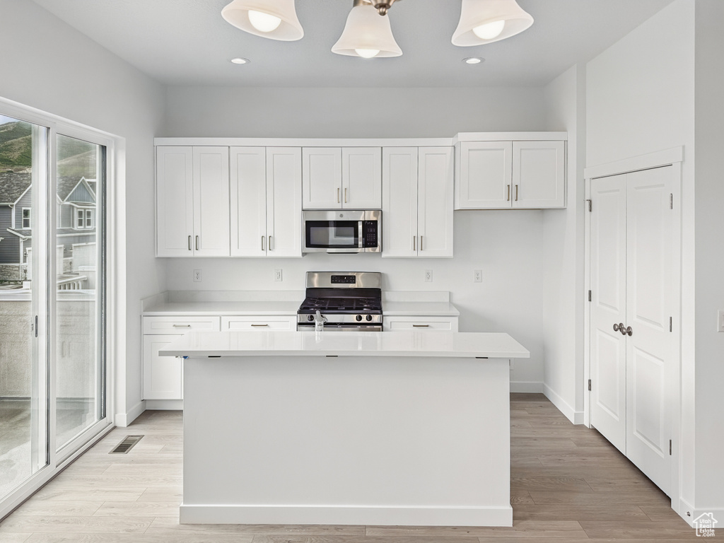Kitchen featuring stainless steel appliances, white cabinets, light wood-type flooring, and recessed lighting