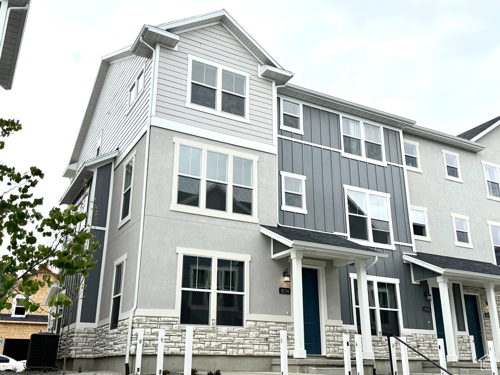 Multi unit property featuring stone siding, central air condition unit, board and batten siding, and stucco siding