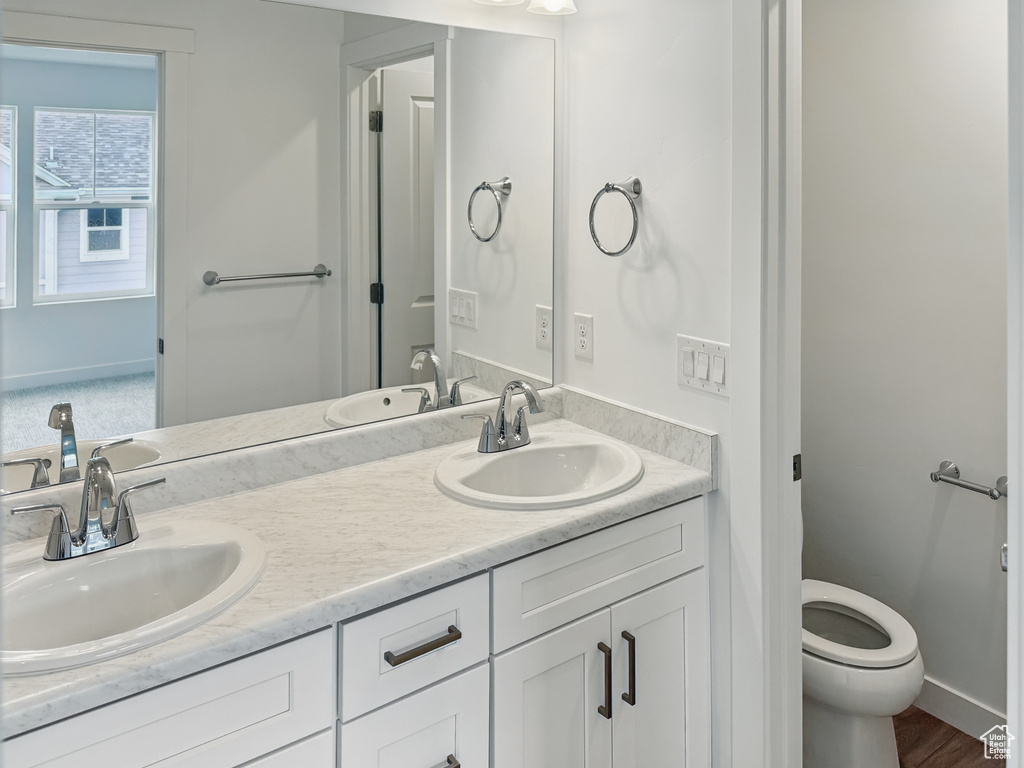 Bathroom featuring toilet, double vanity, and baseboards