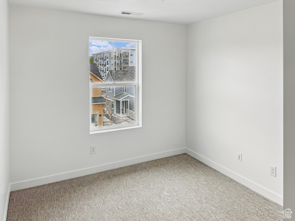 Carpeted spare room featuring baseboards