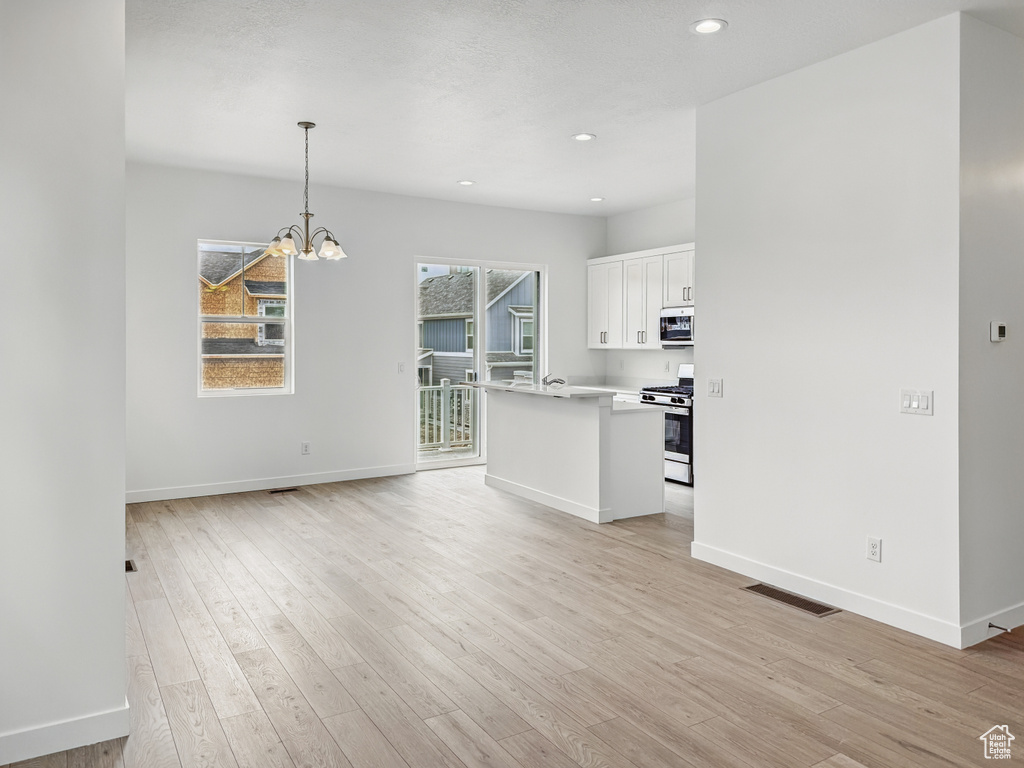 Unfurnished living room with a chandelier, baseboards, light wood-style floors, and recessed lighting