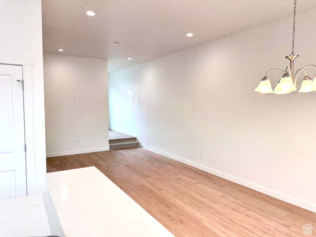 Unfurnished room with wood finished floors, a chandelier, recessed lighting, and baseboards