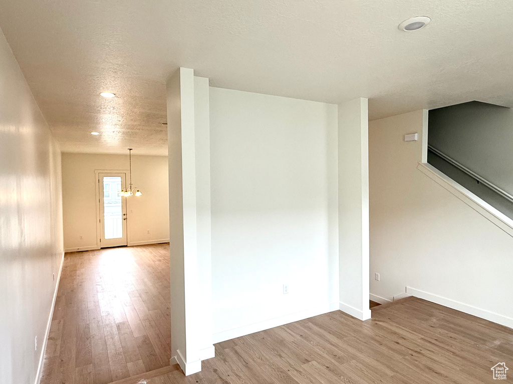 Empty room with wood finished floors, recessed lighting, baseboards, a chandelier, and a textured ceiling