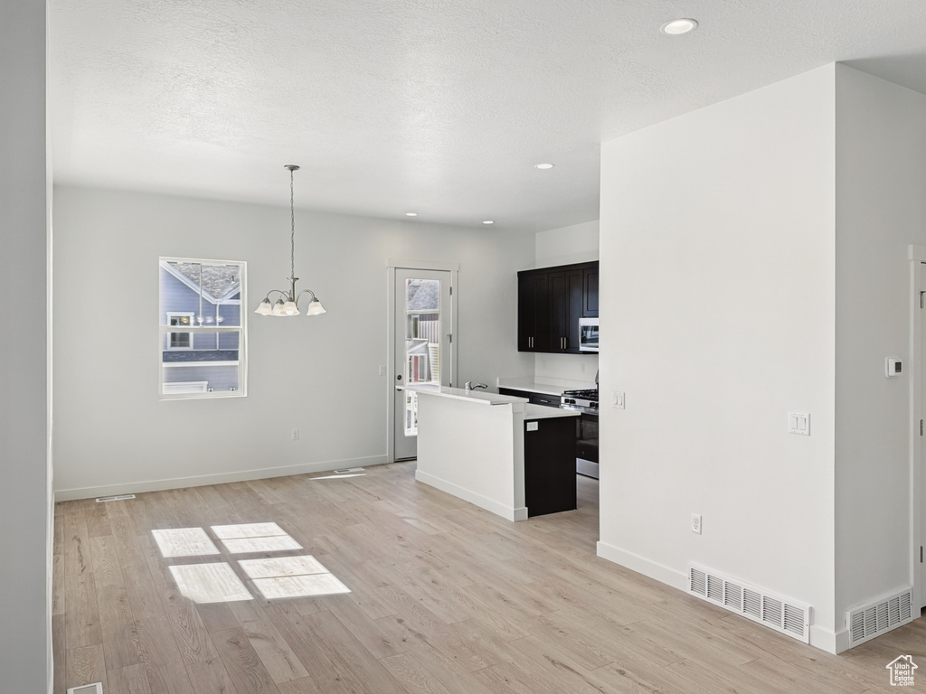 Unfurnished living room with light wood-type flooring, a chandelier, recessed lighting, and baseboards
