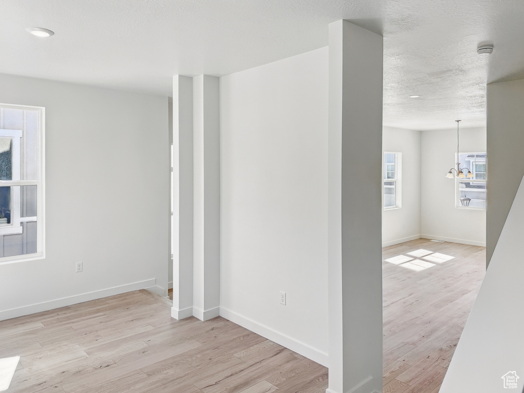 Empty room with wood finished floors, baseboards, a smoke detector, and a textured ceiling