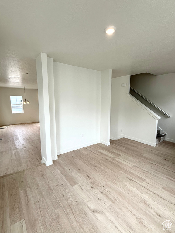 Unfurnished living room with light wood-style floors, stairway, and baseboards
