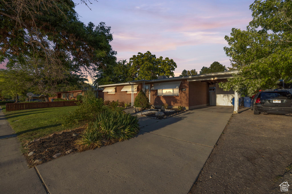 View of front of home featuring brick siding, driveway, a yard, and a carport