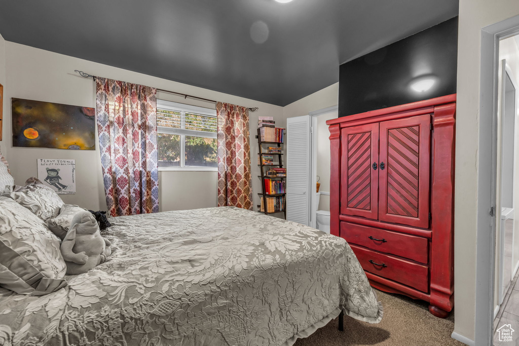 Bedroom with carpet floors, lofted ceiling, and ensuite bathroom