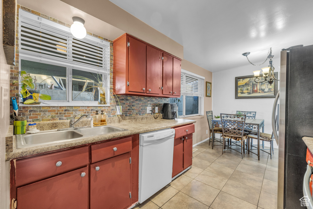 Kitchen with dishwasher, freestanding refrigerator, a sink, light tile patterned floors, and light countertops