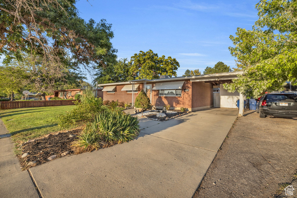 View of front of home with brick siding, concrete driveway, and a carport