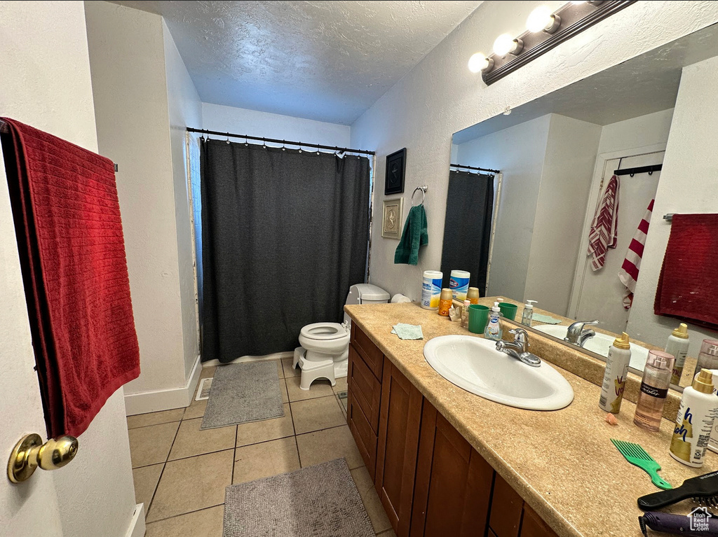 Full bathroom featuring a textured ceiling, tile patterned floors, vanity, toilet, and a shower with curtain