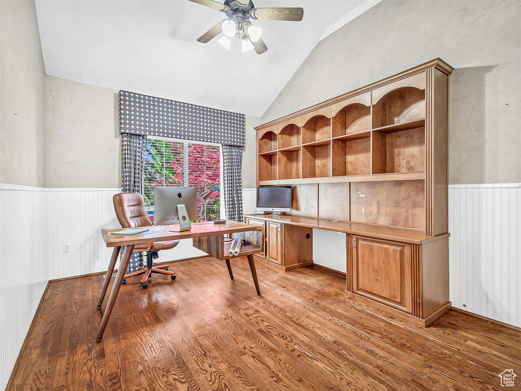 Office featuring lofted ceiling, ceiling fan, a wainscoted wall, and wood finished floors