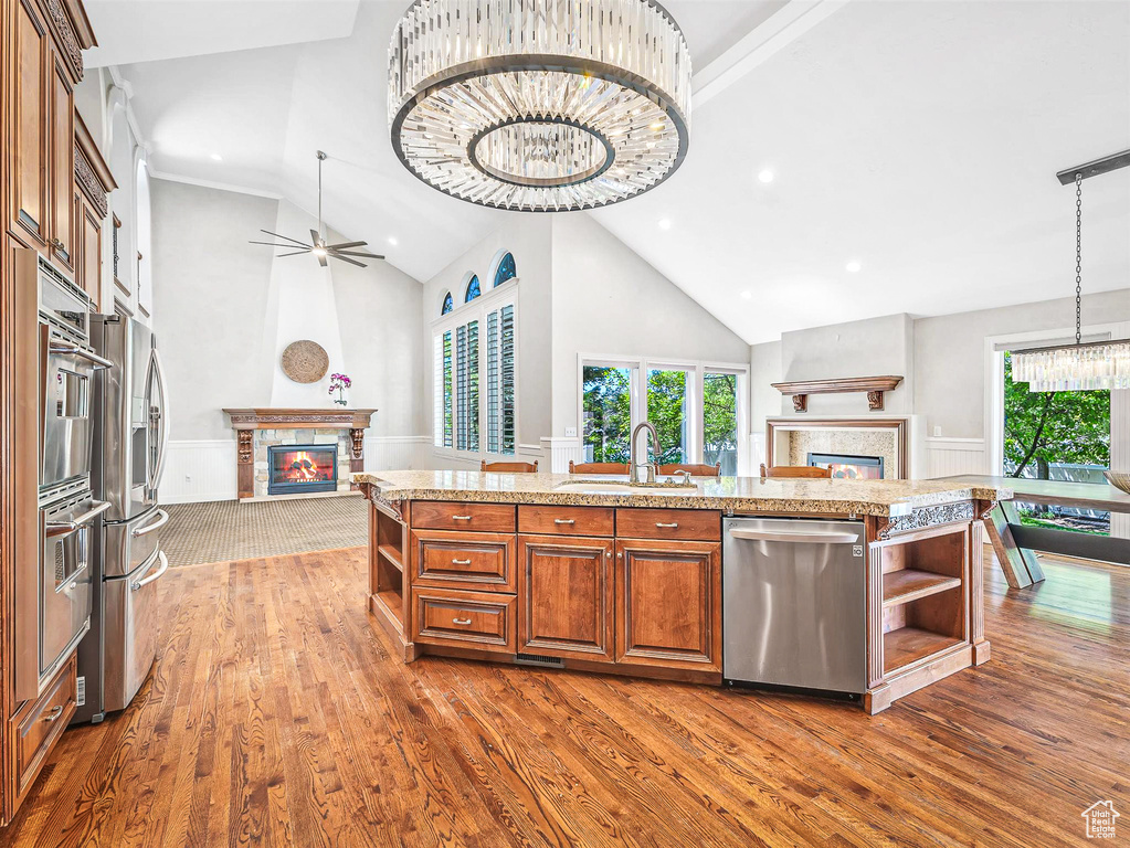 Kitchen with a glass covered fireplace, stainless steel appliances, open shelves, open floor plan, and high vaulted ceiling