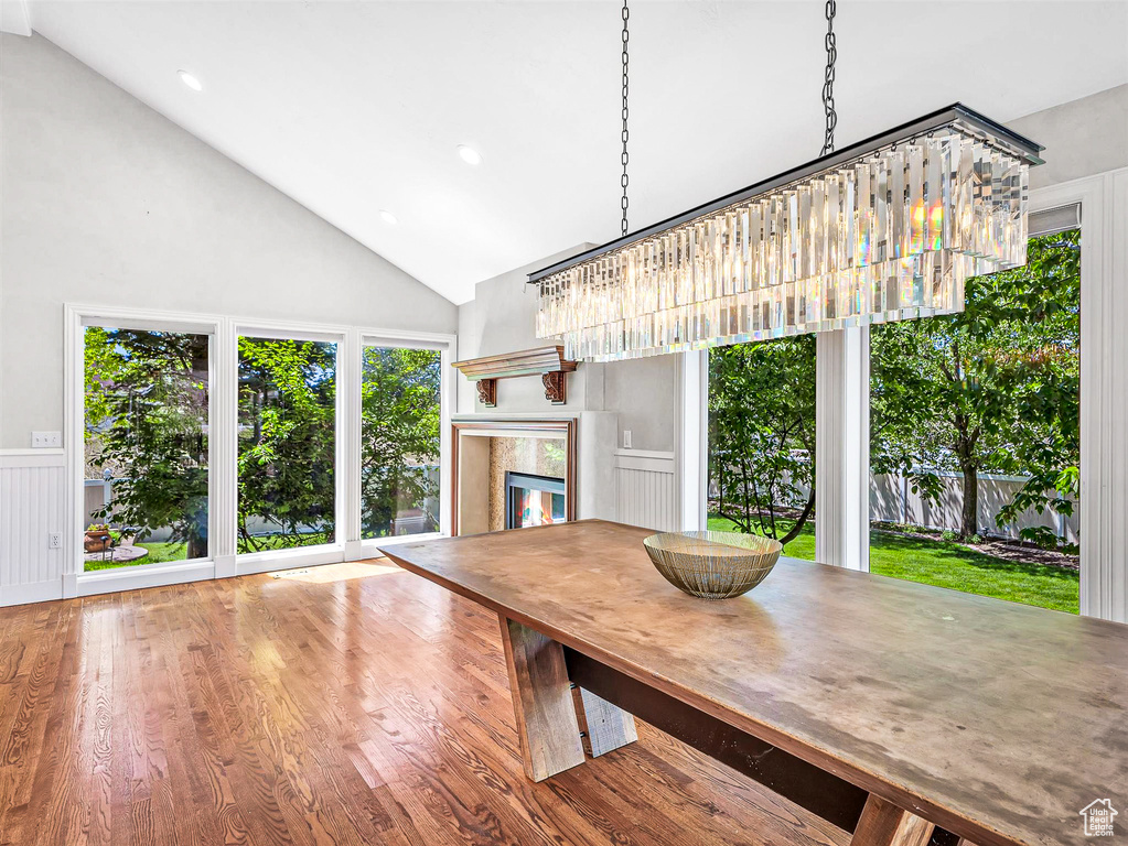 Dining room with high vaulted ceiling, a fireplace, wood finished floors, and healthy amount of natural light