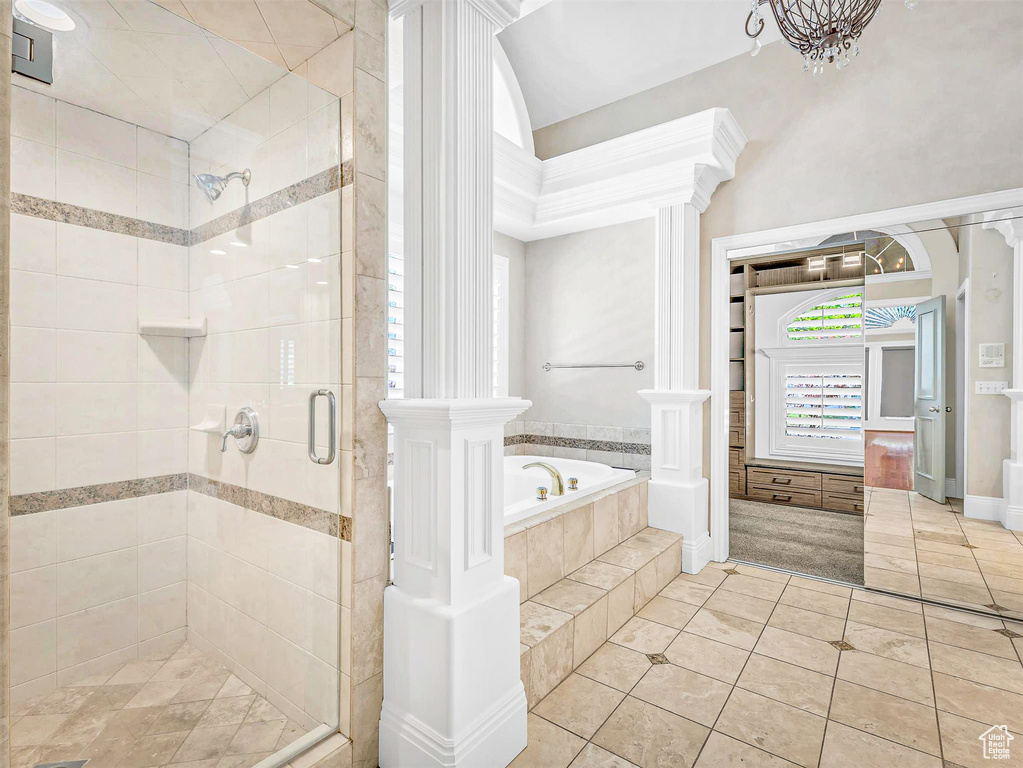 Bathroom with a stall shower, tile patterned floors, a bath, and ornate columns