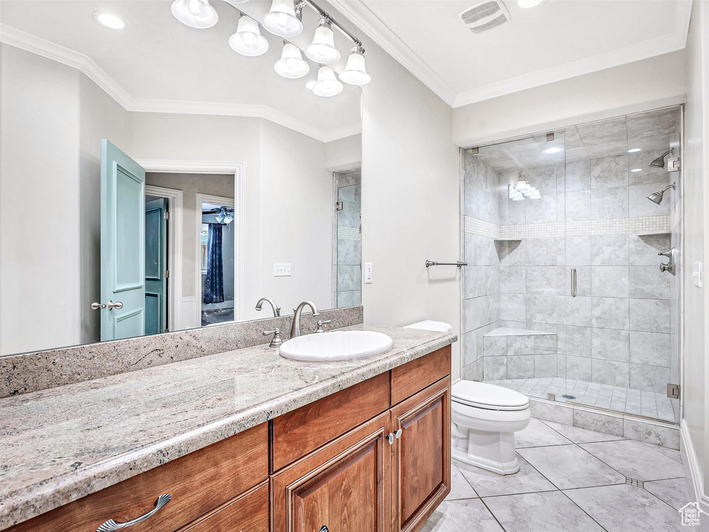 Bathroom featuring a shower stall, toilet, vanity, tile patterned flooring, and crown molding