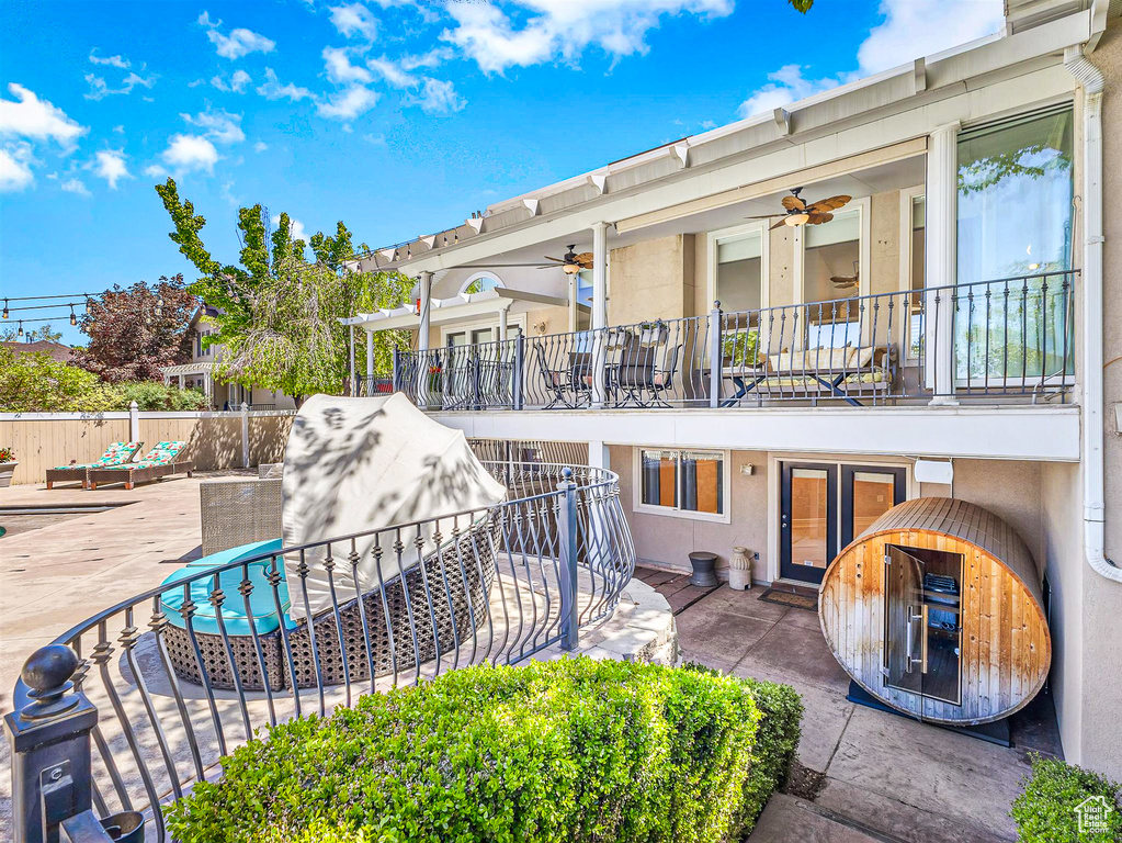 Back of house featuring ceiling fan, a balcony, fence, stucco siding, and a patio area