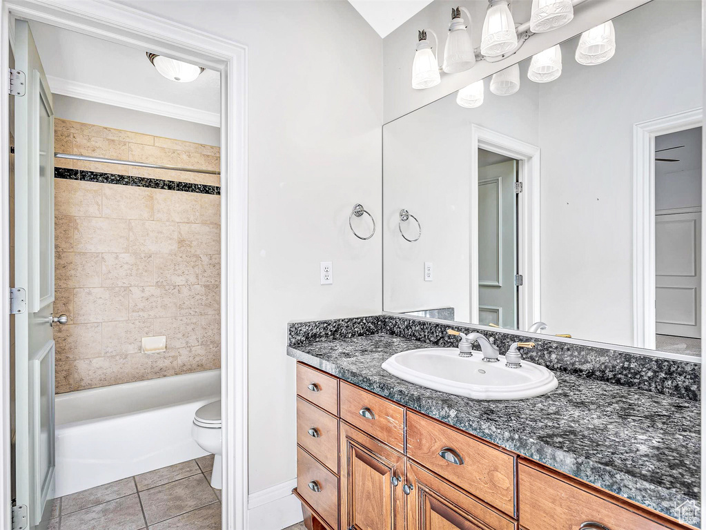 Bathroom featuring tile patterned flooring, toilet, vanity, tub / shower combination, and crown molding