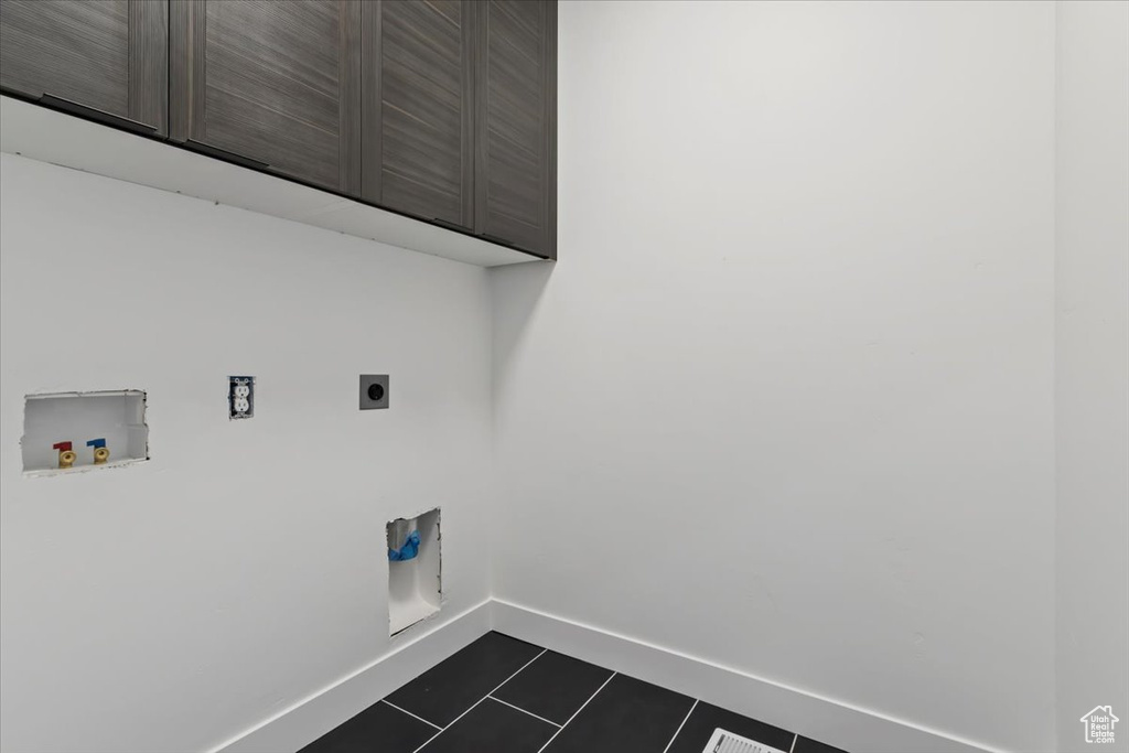 Clothes washing area with cabinet space, electric dryer hookup, washer hookup, baseboards, and dark tile patterned floors